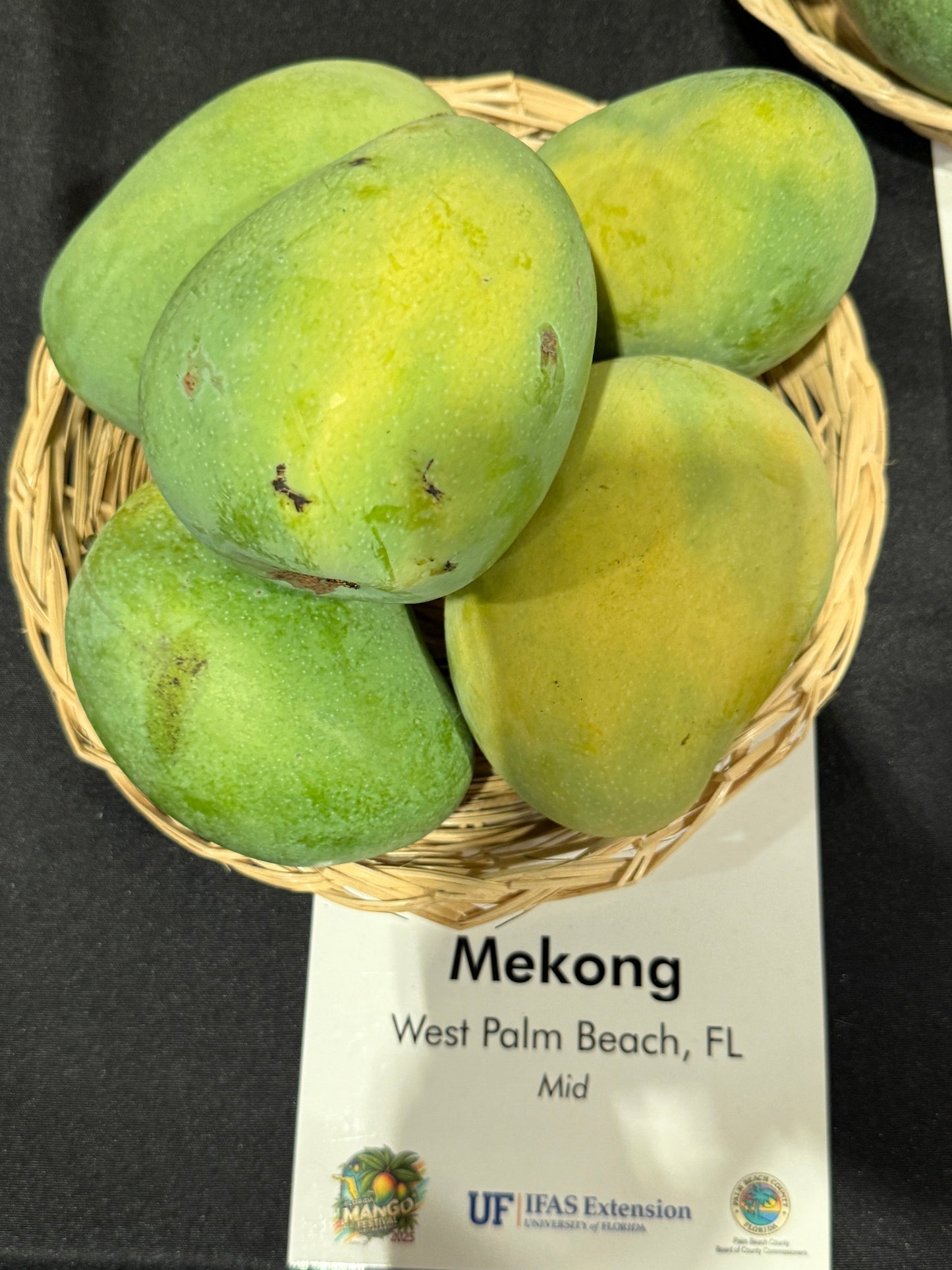Basket of green mangoes on a table with a Mekong label